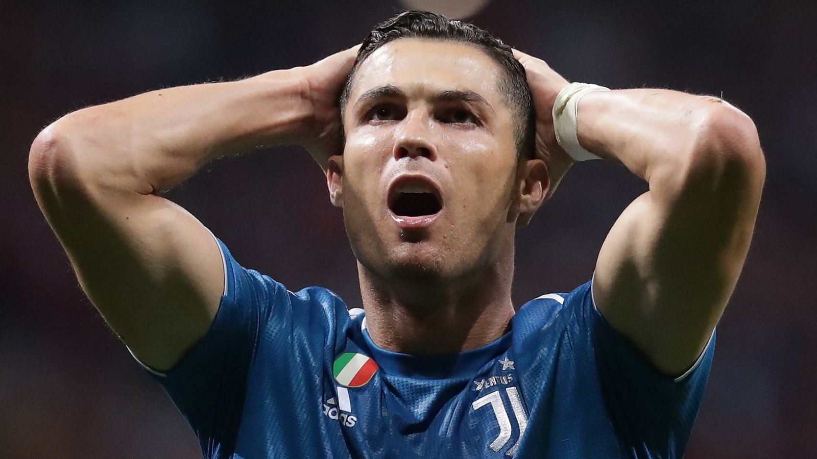 Cristiano Ronaldo, vêtu du maillot bleu de la Juventus, semble frustré, les mains sur la tête, lors d'un moment tendu sur le terrain.