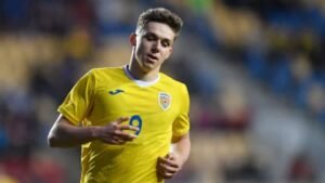 لويس مونتيانو يرتدي زي رومانيا الأصفر الزاهي، يركض في الملعب بتعبير مركز، مسلطاً الضوء على دوره كمهاجم.