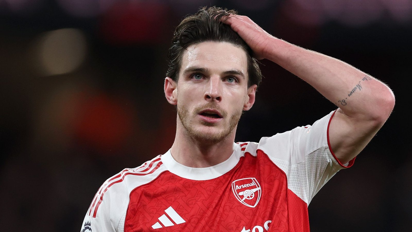 Declan Rice, in het rood-witte tenue van Arsenal, ziet er met zijn hand op zijn hoofd bedrukt uit tijdens een gespannen moment op het veld.