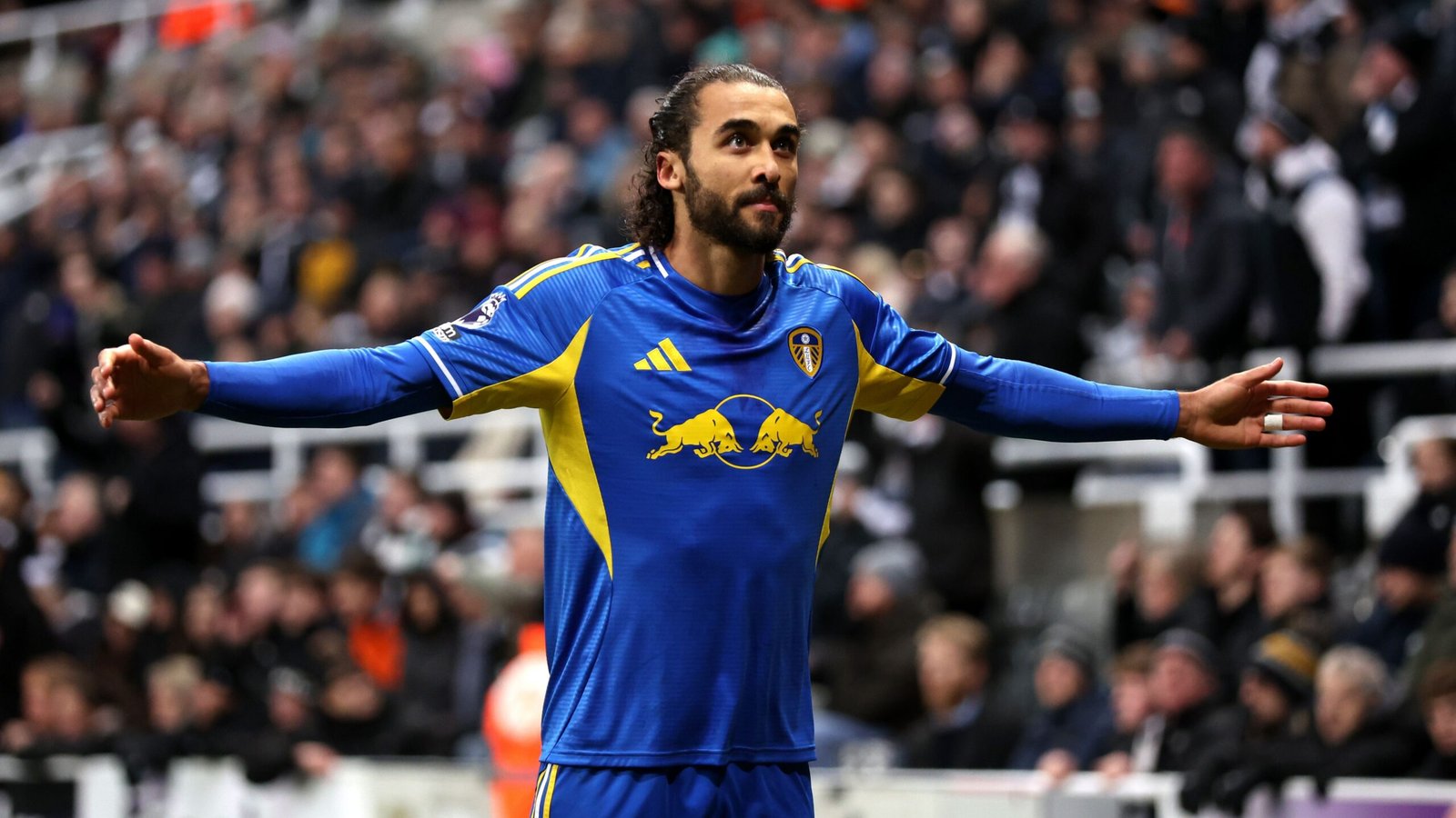 Dominic Calvert-Lewin juicht in het blauw-gele tenue van Leeds, met uitgestrekte armen, te midden van een enthousiaste menigte op de achtergrond.