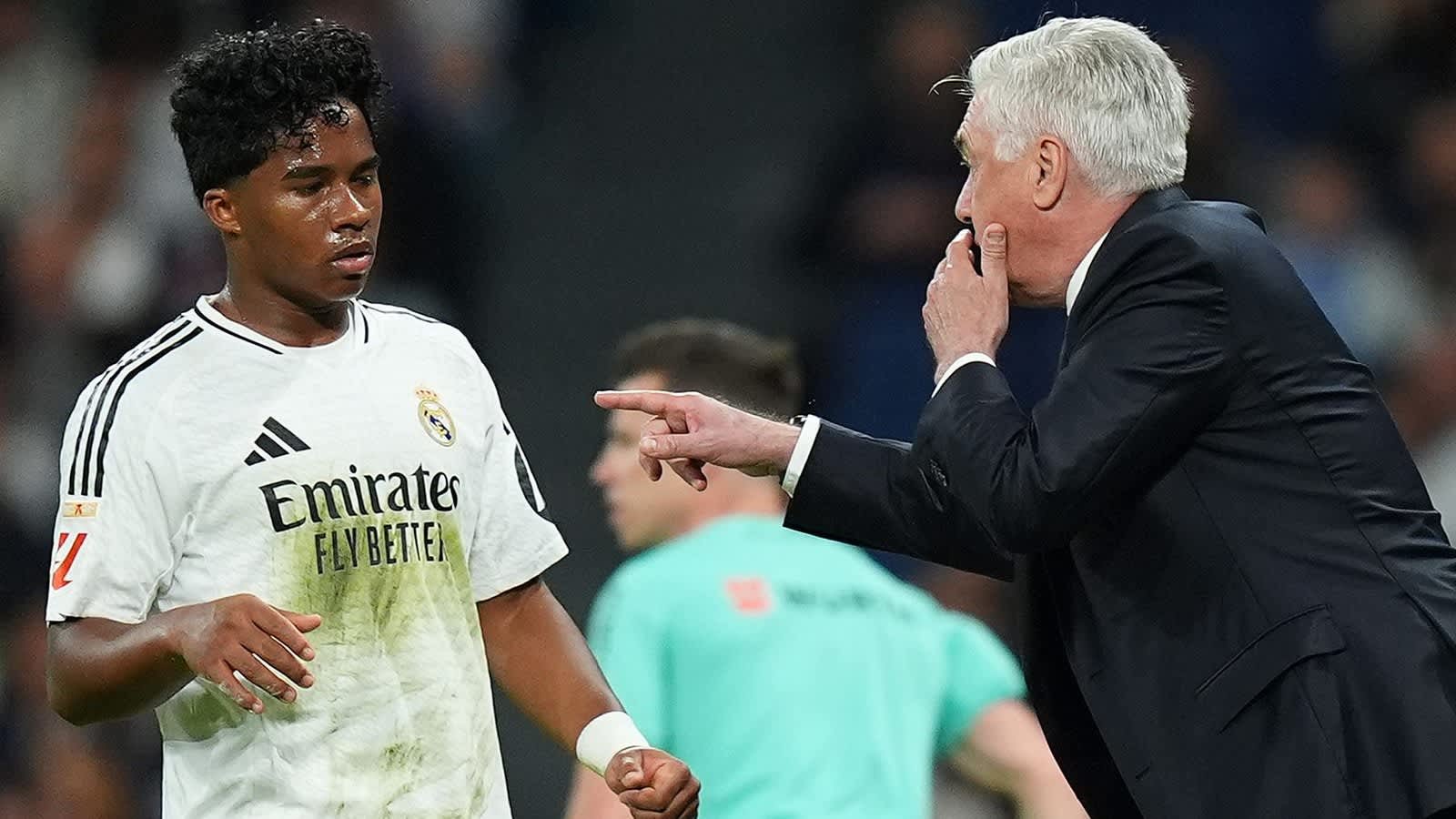 Endrick, dans un maillot du Real Madrid taché, regarde Carlo Ancelotti, qui gesticule avec animation pendant un match, exprimant de l'urgence.