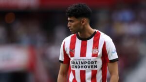 Ricardo Pepi in PSV's rood-wit gestreepte tenue, geconcentreerd op het spel met een intense uitdrukking tijdens een wedstrijd.