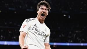 Gonzalo Garcia célèbre avec passion après avoir inscrit un triplé pour le Real Madrid, portant le maillot blanc de l'équipe arborant le logo du sponsor 'Emirates'.