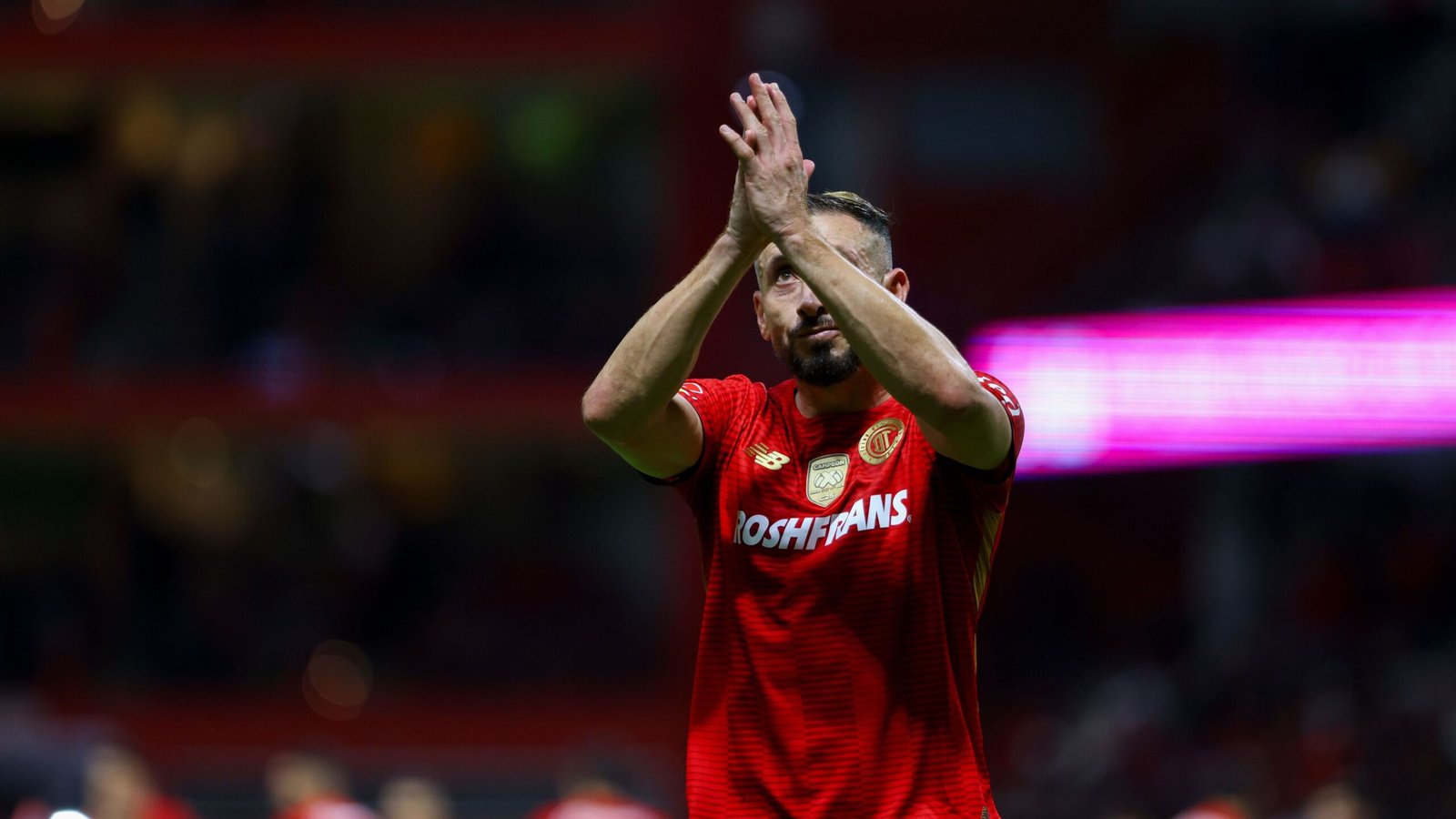 Hector Herrera applaudisseert voor fans in een rood Houston Dynamo-tenue, toont teamgeest na een wedstrijdviering.