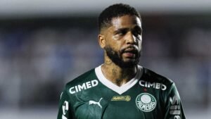 Défenseur portant un maillot vert du Palmeiras avec le sponsoring 'Cimed', affichant une expression intense pendant un match, reflétant la concentration et la détermination.