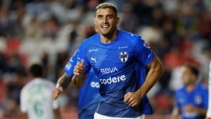 Germán Berterame juicht na een doelpunt voor Monterrey, gekleed in het blauwe thuistenue van de club met sponsorlogo's, en toont opwinding en teamgeest.