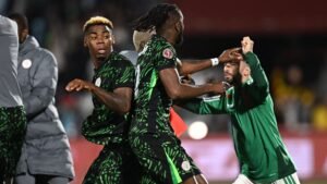 Nigeriaanse spelers in levendige groene tenues confronteren een Marokkaanse speler in het groen, tijdens een gespannen moment in de AFCON-kwartfinales.
