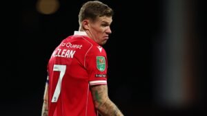 James McClean in a red jersey, number 7, showing frustration during a match. He wears captain's armband and an EFL badge.