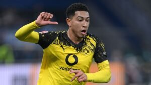 Jude Bellingham in een levendig Borussia Dortmund-tenue viert een geslaagde actie, wat zijn dynamische beweging en passie voor het spel laat zien.
