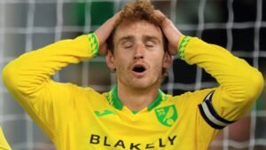 Le capitaine de Norwich City, Josh Sargent, l'air angoissé, les mains sur la tête, dans son équipement de gardien de but jaune vif lors d'un moment tendu.