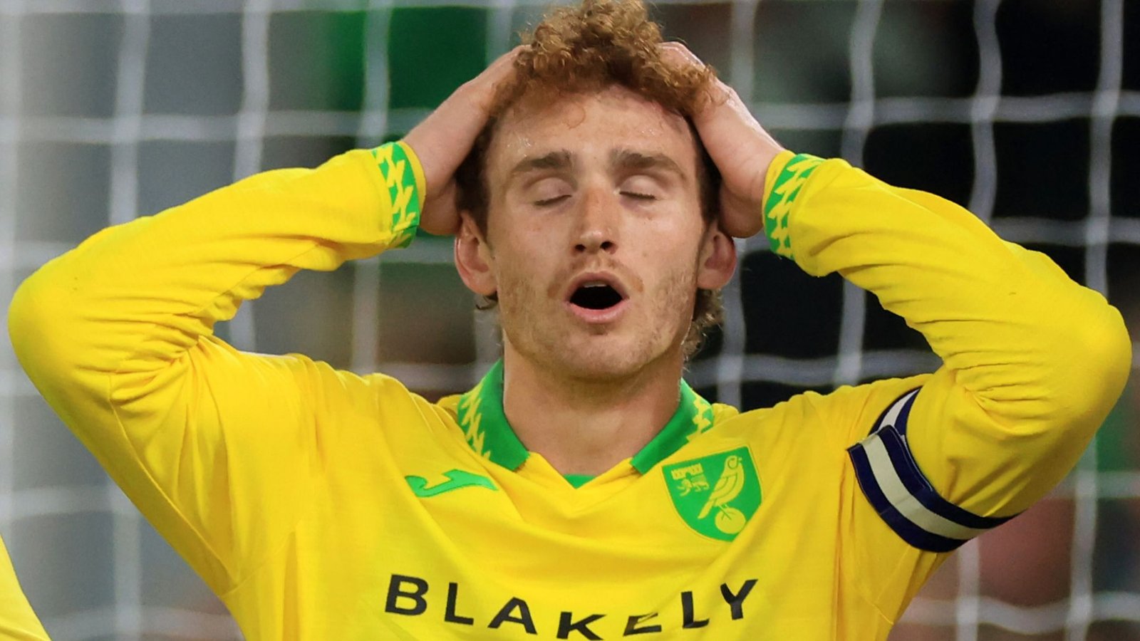 Le capitaine de Norwich City, Josh Sargent, l'air angoissé, les mains sur la tête, dans son équipement de gardien de but jaune vif lors d'un moment tendu.