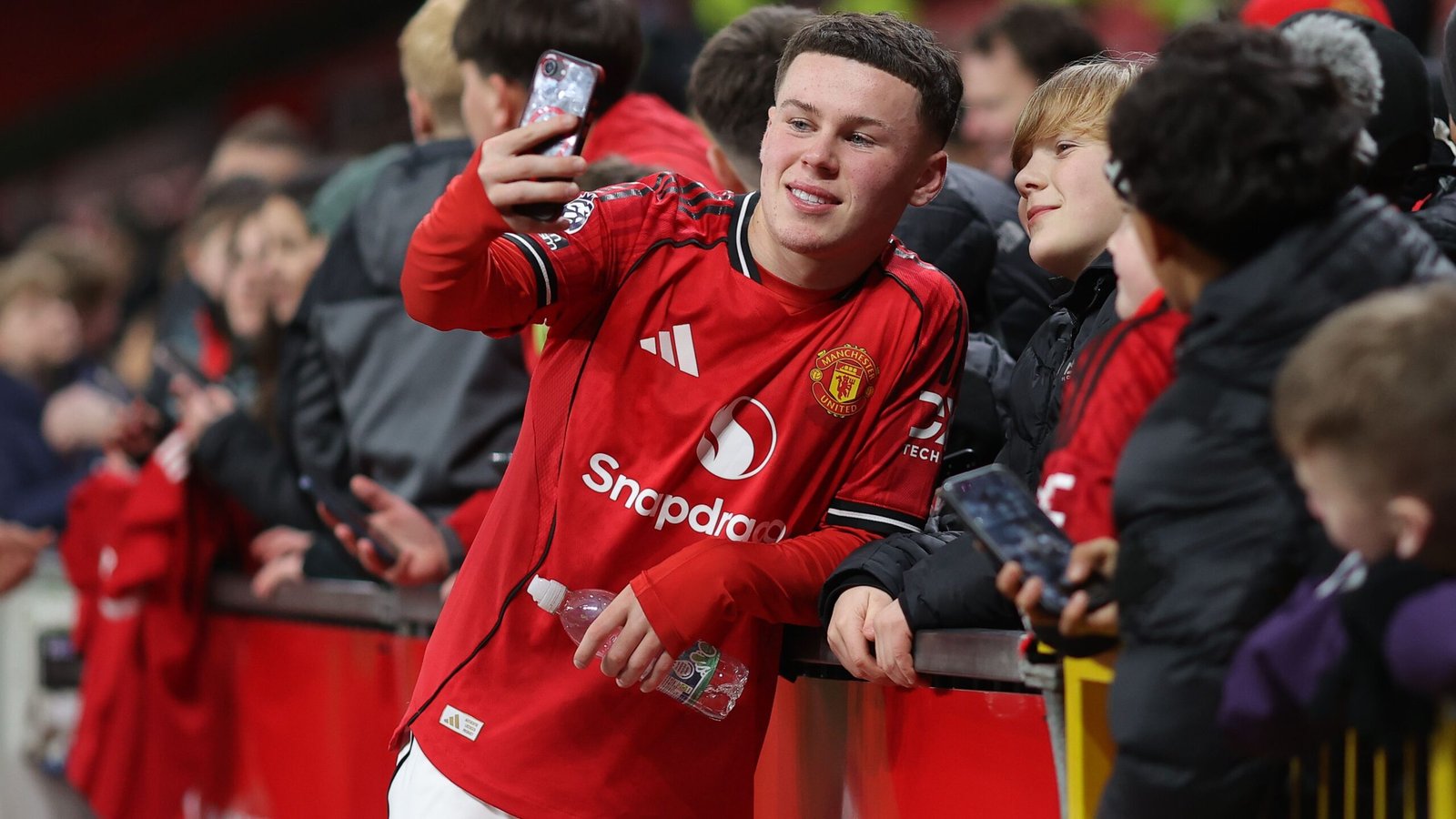Kai Rooney maakt een selfie in zijn Manchester United-tenue terwijl fans juichen tijdens zijn eerste competitieve optreden op Old Trafford.