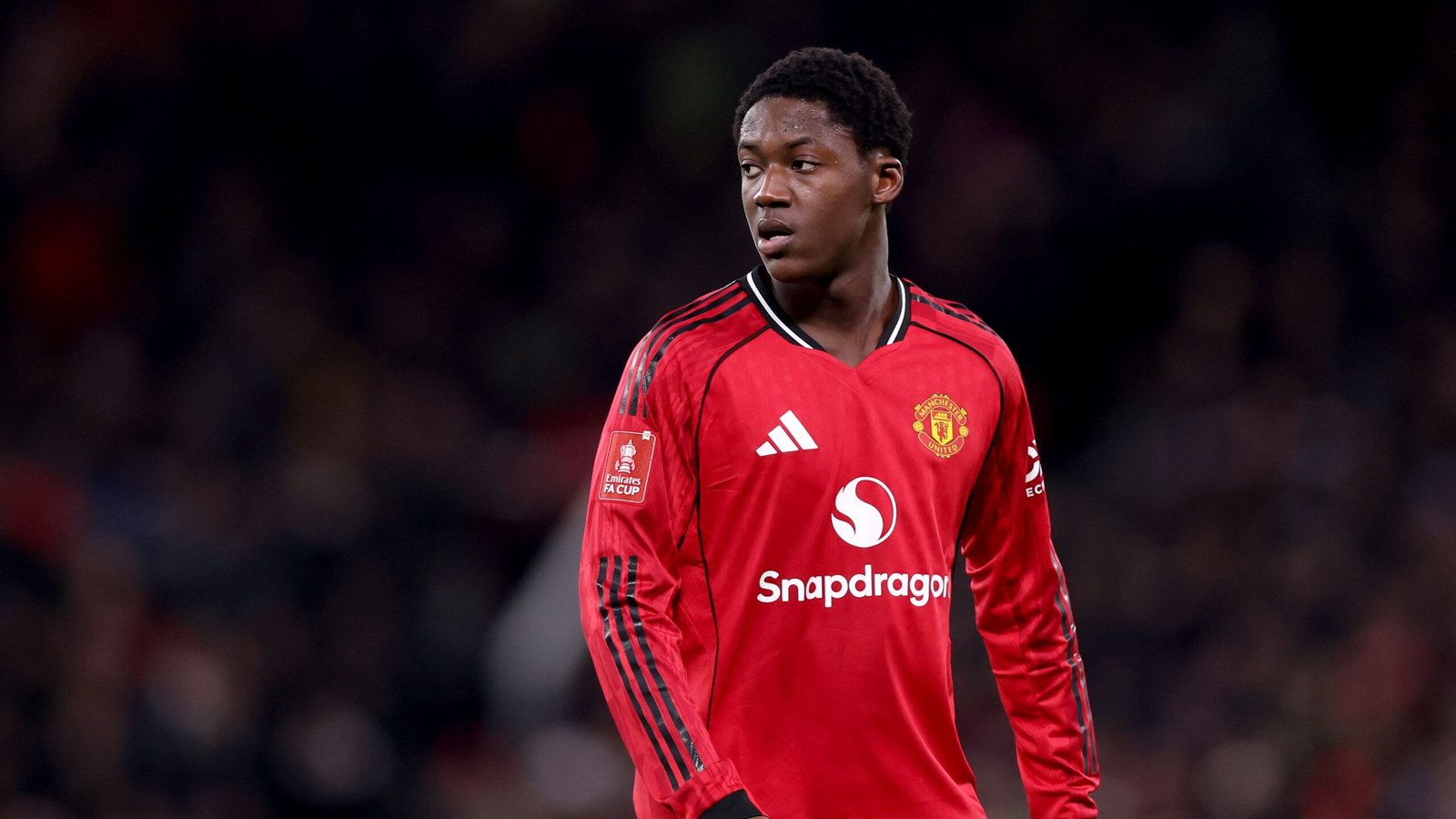 Kobbie Mainoo draagt het rode tenue van Manchester United tijdens een FA Cup-wedstrijd, met een gefocuste uitdrukking op het veld.