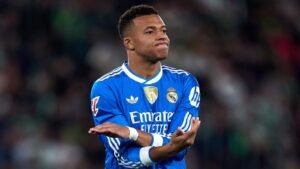 Kylian Mbappé in een blauw Real Madrid-tenue gebaart gefrustreerd tijdens een wedstrijd, wat zijn vastberadenheid onderstreept om volledige fitheid te herwinnen.