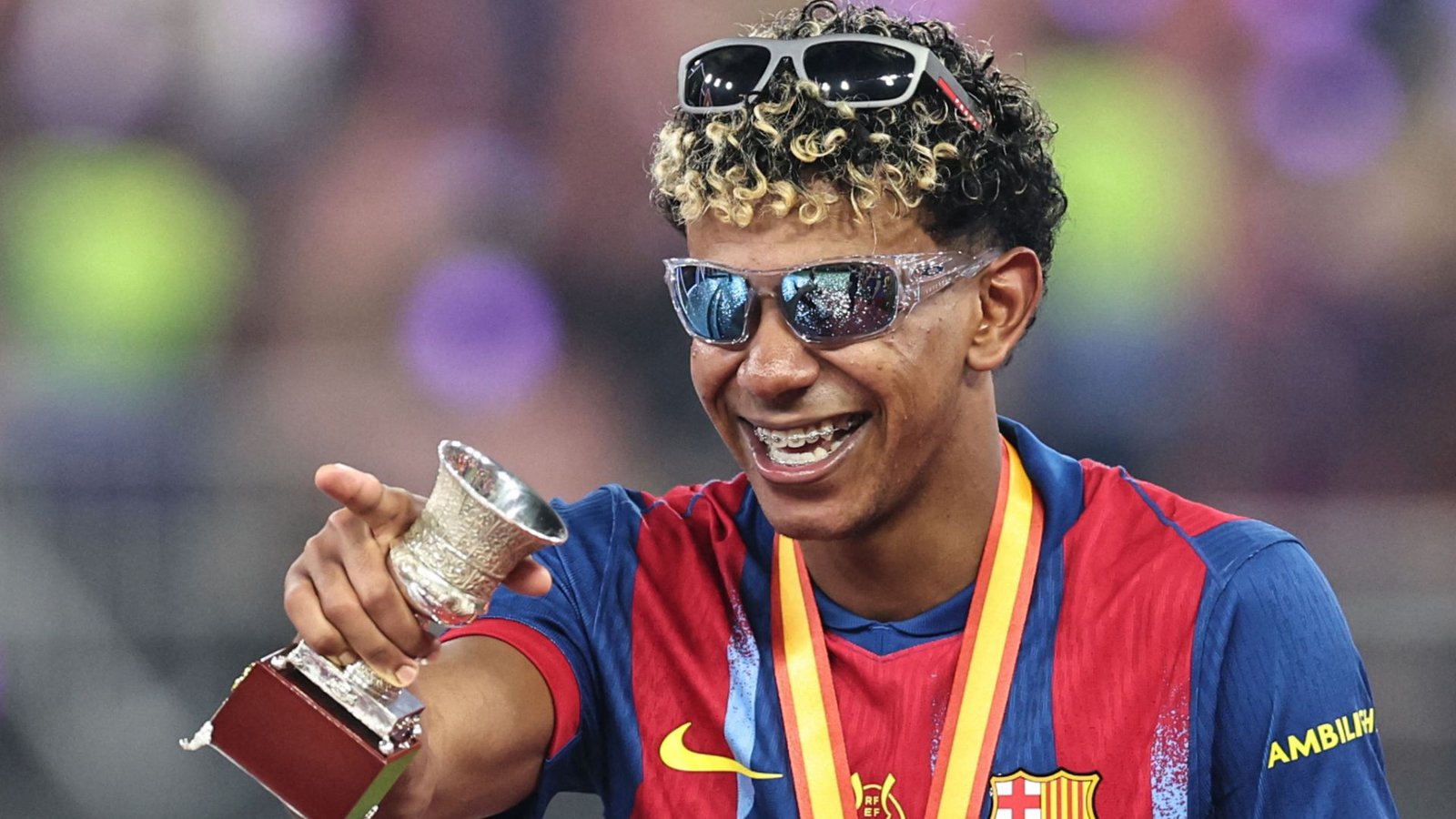 Lamine Yamal viert met een trofee, draagt een zonnebril en een Barcelona-outfit, en toont zijn vreugde na een recente overwinning.