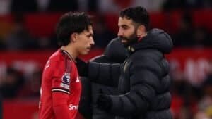 Lisandro Martínez, vêtu du maillot rouge de Manchester United, partage un moment avec l'entraîneur Ruben Amorim, tous deux affichant de la concentration en tenue d'entraînement.