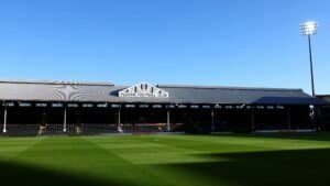 Le Craven Cottage de Fulham FC sous un ciel bleu dégagé, présentant un terrain vert impeccable et la tribune emblématique avant un match contre Liverpool.