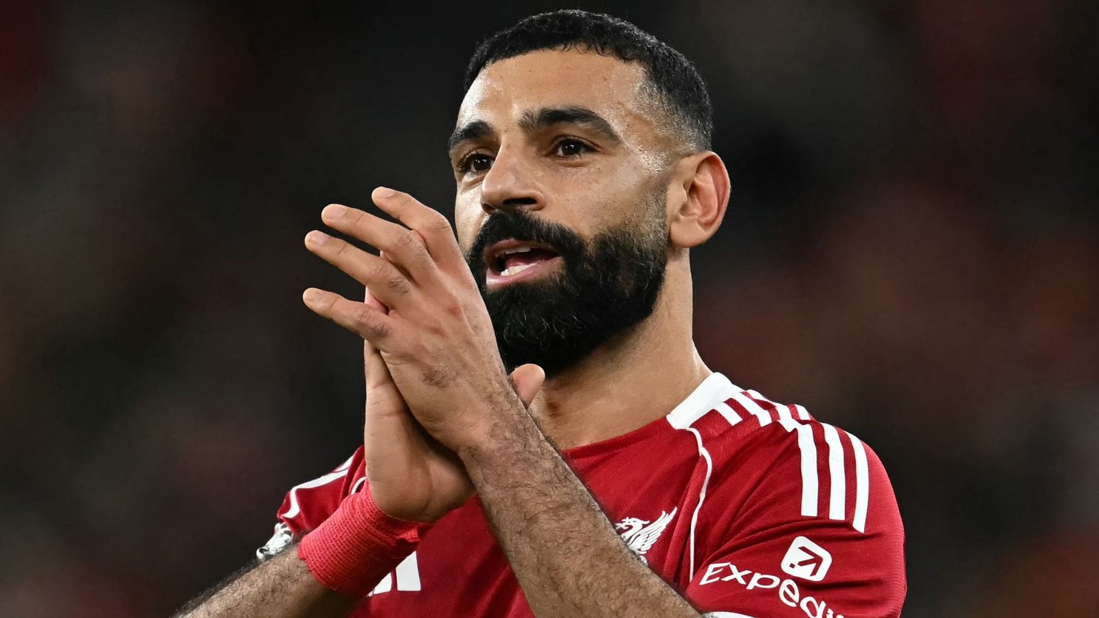 Mohamed Salah, vêtu du maillot rouge de Liverpool, gesticule avec passion pendant un match, démontrant son intensité et son leadership sur le terrain.