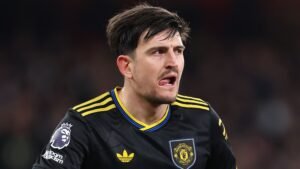 Harry Maguire in het zwarte tenue van Manchester United, toont intense concentratie en vastberadenheid tijdens een wedstrijd, met het Premier League-logo op zijn mouw.