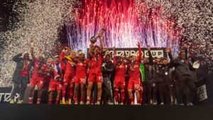 Des joueurs célébrant, vêtus de maillots rouges, soulèvent le trophée au milieu des confettis et des feux d'artifice lors de la cérémonie de la MLS Next Pro Cup.