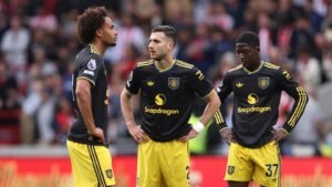 Les joueurs de Manchester United ont l'air abattus sur le terrain, portant leur tenue extérieure noire avec des accents jaunes pendant un moment tendu du match.