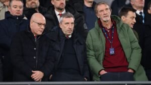 Manchester United-directeur Jason Wilcox onder de fans, met uitdrukkingen van bezorgdheid of ongenoegen op Old Trafford tijdens een gespannen wedstrijdsfeer.