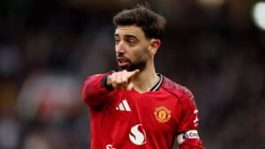 Bruno Fernandes, vêtu du maillot rouge de Manchester United, gesticule avec intensité pendant un match, illustrant son leadership et sa concentration.