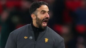 Ruben Amorim criant avec passion sur la ligne de touche, vêtu d'une veste sombre arborant le logo du club, lors d'un match de football intense.