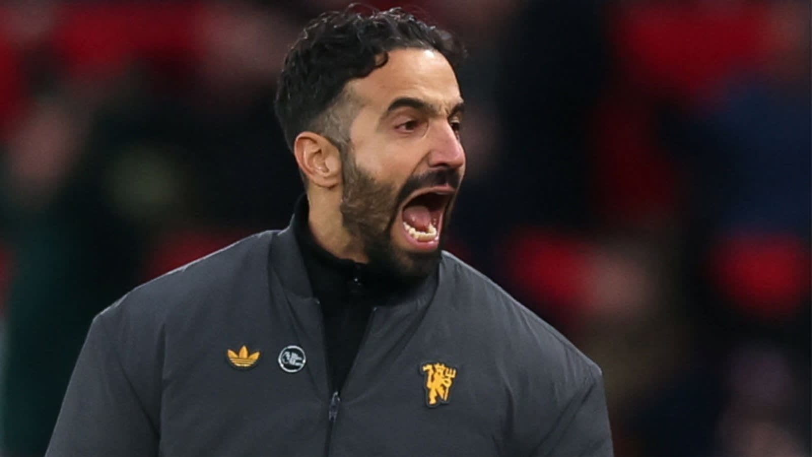 Ruben Amorim criant avec passion sur la ligne de touche, vêtu d'une veste sombre arborant le logo du club, lors d'un match de football intense.