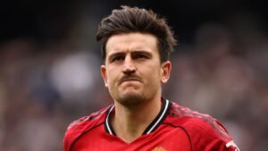 Harry Maguire in een rood tenue van Manchester United, met serieuze uitdrukking tijdens een wedstrijd, wat de onzekerheid over zijn toekomst bij de club weerspiegelt.