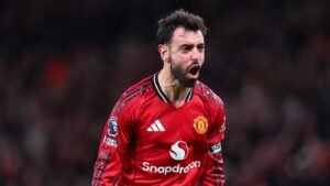 Bruno Fernandes célèbre avec passion dans le maillot rouge domicile de Manchester United, démontrant sa détermination pendant un match.