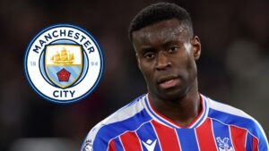 Marc Guehi in het tenue van Crystal Palace, met het logo van Manchester City achter hem, wat de recente transferspeculatie benadrukt.