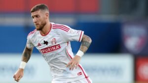 Marcel Hartel sprint in een wit-rood St. Louis CITY SC-tenue tijdens een wedstrijd, waarbij hij intense focus en vastberadenheid tentoonspreidt.