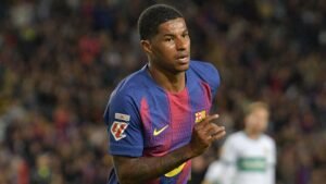 Marcus Rashford in de iconische kastanjebruine en blauwe outfit van Barcelona, gefocust op het spel tijdens een wedstrijd, en toont vastberadenheid op het veld.