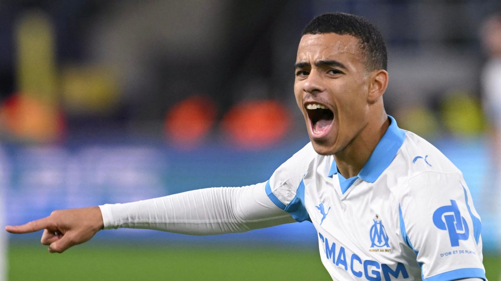 Mason Greenwood viert uitbundig na het scoren van een hattrick, terwijl hij het wit en hemelsblauwe tenue van Marseille draagt tijdens een wedstrijd.