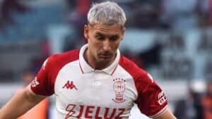 Matko Miljevic portant un maillot de football blanc et rouge, concentré sur le match, représentant le football club marocain.