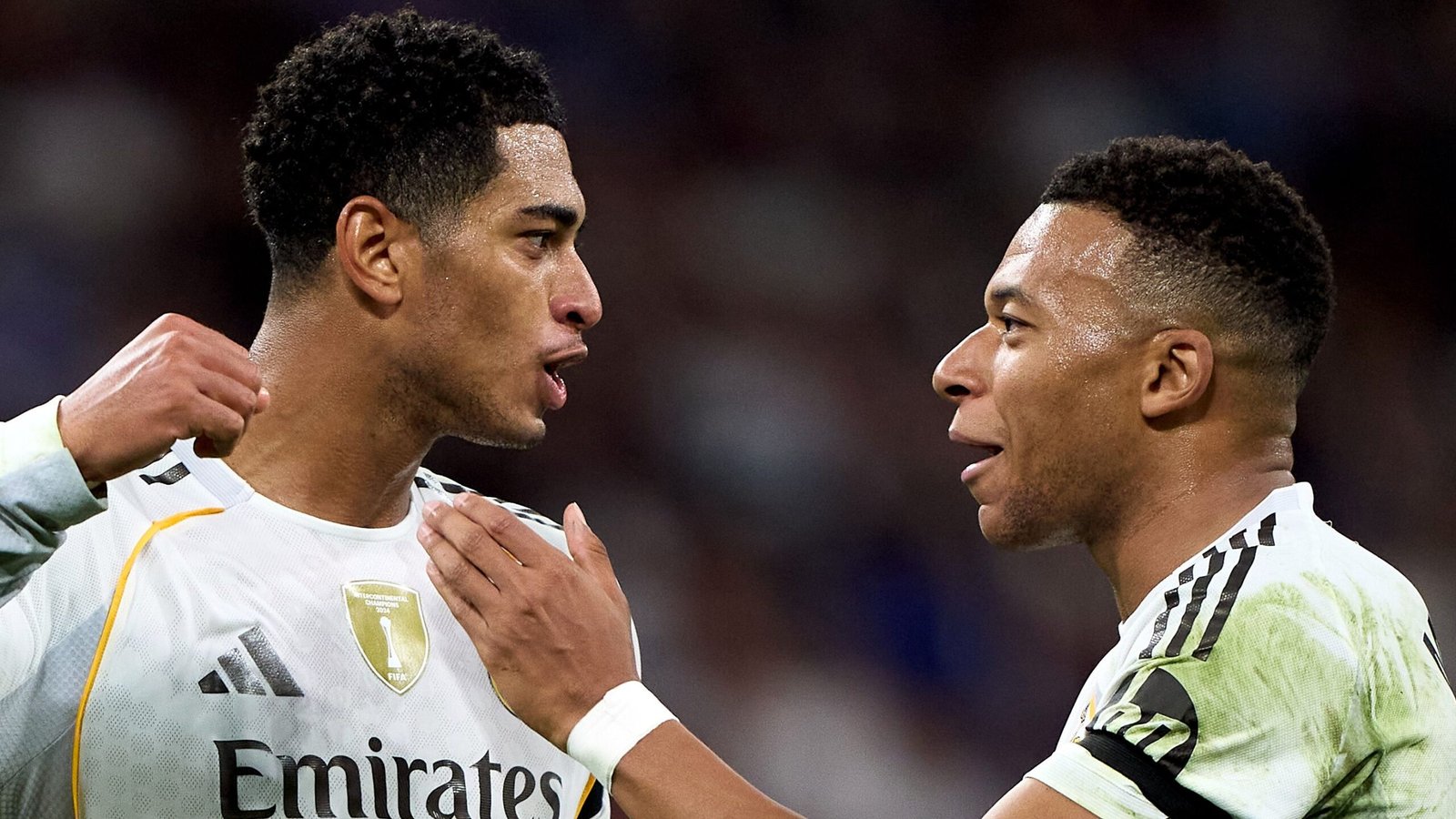 Bellingham en Mbappé delen een moment op het veld, gekleed in Real Madrid-tenues, vieren een wedstrijdzege met intense uitdrukkingen.