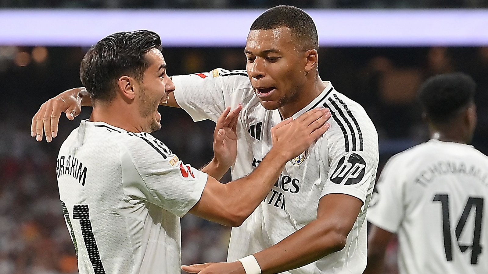 Brahim Diaz en Kylian Mbappé vieren samen een doelpunt, in hun witte Real Madrid-tenues, en tonen vreugde op het veld.