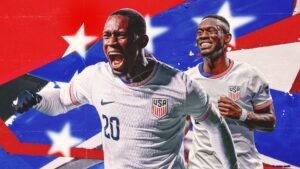 Folarin Balogun viert in het US nationale teamtenue, tegen een levendige rood-blauwe achtergrond met sterren, belichaamt opwinding voor het WK 2026.