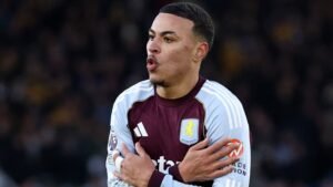 Morgan Rogers viert gepassioneerd in het kastanjebruin-blauwe tenue van Aston Villa, vreugde uitend na een belangrijk wedstrijdmoment.