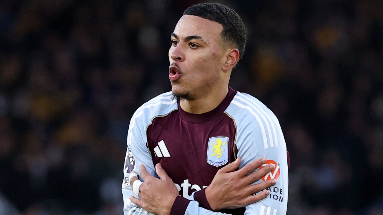 Morgan Rogers viert gepassioneerd in het kastanjebruin-blauwe tenue van Aston Villa, vreugde uitend na een belangrijk wedstrijdmoment.