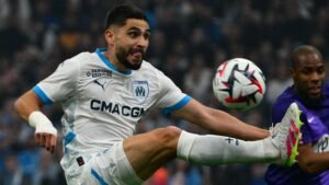 Neal Maupay of Marseille stretches to intercept the ball in action against a goalkeeper, showcasing intense determination during the match.