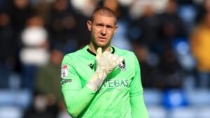 Ethan Horvath in een felgroen keepers-tenue, gebarend met zijn gehandschoende hand tijdens een wedstrijd, met wazige fans op de achtergrond.