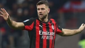Niclas Füllkrug gebaart tijdens een wedstrijd, gekleed in een zwart-rood gestreept AC Milan-tenue, en toont focus en vastberadenheid.