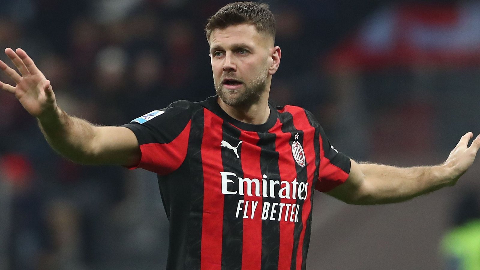 Niclas Füllkrug gebaart tijdens een wedstrijd, gekleed in een zwart-rood gestreept AC Milan-tenue, en toont focus en vastberadenheid.