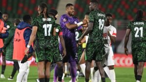 Les joueurs nigérians en maillots verts se serrent la main après le match, l'accent étant mis sur le gardien de but en violet et ses coéquipiers célébrant ensemble.