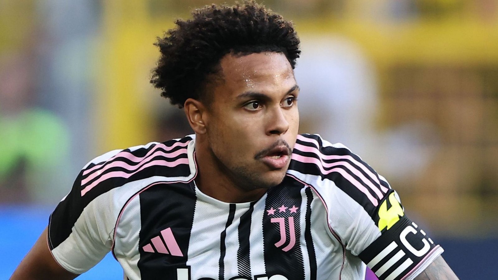 Weston McKennie in het zwart-roze gestreepte tenue van Juventus tijdens een wedstrijd, geconcentreerd en in actie, met het clubembleem op het shirt.