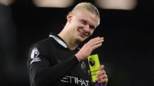يبتسم إيرلينغ هالاند ويلوح وهو يحمل جائزة أفضل لاعب في المباراة بالدوري الإنجليزي الممتاز، مرتديًا زي مانشستر سيتي الأسود.