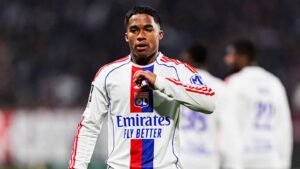 لاعب ليون يرتدي زيًّا أبيض مع لمسات حمراء وزرقاء، ويظهر شعار "طيران الإمارات تحلق بشكل أفضل"، يؤشر بإيماءات على أرض الملعب خلال المباراة.