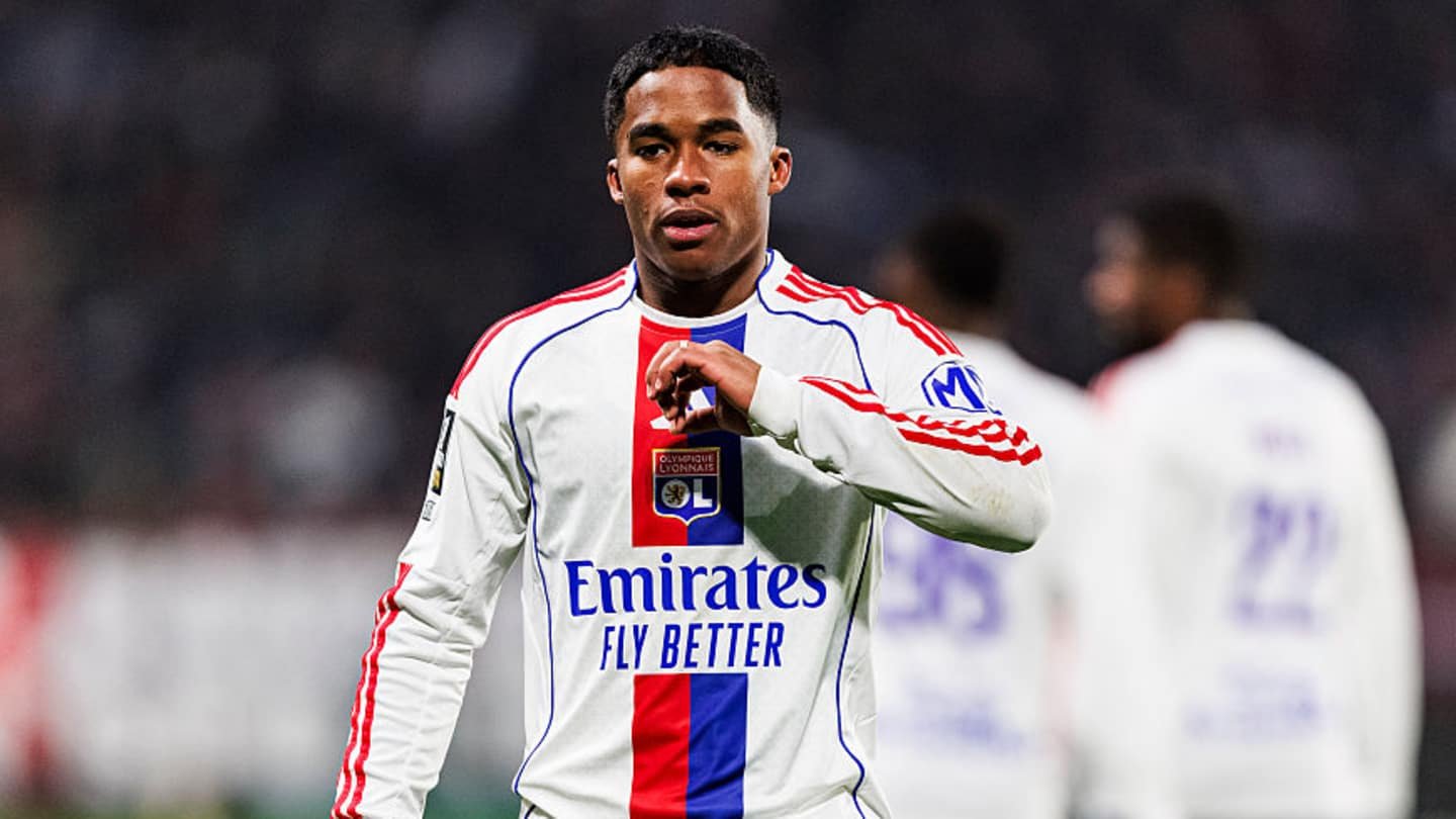 لاعب ليون يرتدي زيًّا أبيض مع لمسات حمراء وزرقاء، ويظهر شعار "طيران الإمارات تحلق بشكل أفضل"، يؤشر بإيماءات على أرض الملعب خلال المباراة.